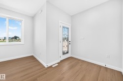 Entryway featuring wood-finish flooring, white walls, a window, and a door with decorative glass panels - 