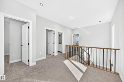 Carpeted landing featuring recessed lighting, a window, and a wood-finish and black metal railing - 