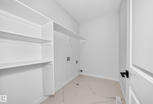 Built-in shelving, white walls, light-toned flooring, and a black door handle - 9 Tilia Place, Spruce Grove, AB 