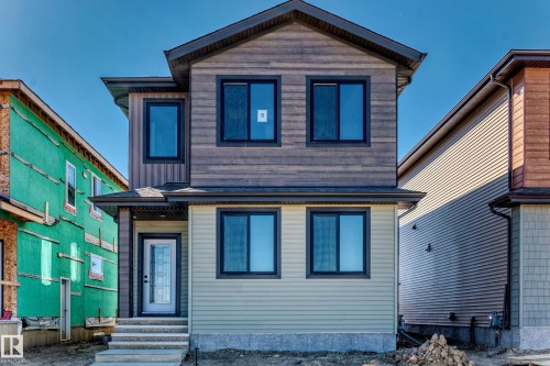 Two-story exterior with multi-toned siding, black-framed windows, and a partially glass-paneled front door - 9 Tilia Place, Spruce Grove, AB 