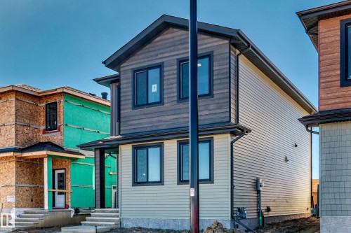 Two-story residence featuring varied exterior siding, dark-framed windows, a covered front entry, and a dark shingle roof - 9 Tilia Place, Spruce Grove, AB 