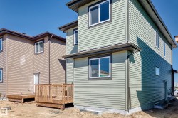 Light green horizontal siding exterior with dark trim accents, white-framed windows, and a foundation - 