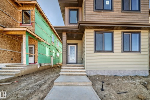 Two-story residential building with light-colored siding, dark-framed windows, and a concrete walkway - 9 Tilia Place, Spruce Grove, AB 