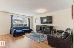 Living area featuring wood-finish flooring, a contemporary light fixture, and a large window - 