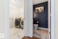 Dedicated laundry area featuring white panel doors, a ceiling-mounted light fixture, and marble-look flooring - 