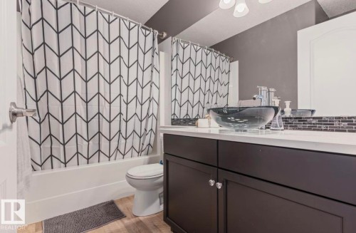 Bathroom featuring a dark wood vanity with a white countertop and clear vessel sink - 1007 Macewan Close Sw, Edmonton, AB - Indoor Photo Showing Bathroom