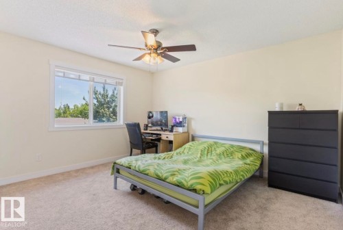 Carpeted room featuring a large window, a ceiling fan, and light-toned walls - 1007 Macewan Close Sw, Edmonton, AB - Indoor Photo Showing Bedroom