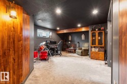 Finished lower level featuring recessed lighting, a wood-finish accent wall, and a visible support beam - 