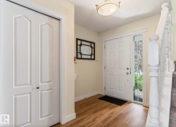 Entryway featuring a paneled door with sidelight, wood-finish flooring, and a white balustrade staircase - 