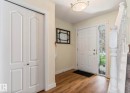 Entryway featuring a paneled door with sidelight, wood-finish flooring, and a white balustrade staircase - 1007 Macewan Close Sw, Edmonton, AB  - Indoor Photo Showing Other Room 