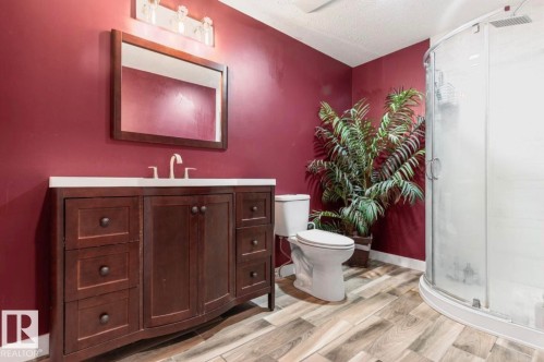 Bathroom featuring wood-finish flooring, a dark wood vanity with a white countertop, and a glass-enclosed corner shower - 1007 Macewan Close Sw, Edmonton, AB - Indoor Photo Showing Bathroom
