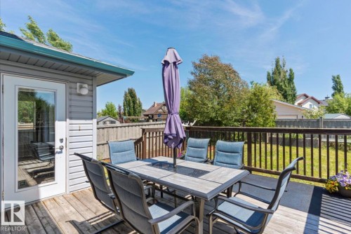 Spacious wooden deck with dark wood railings and a clear glass paneled door - 1007 Macewan Close Sw, Edmonton, AB - Outdoor With Deck Patio Veranda With Exterior