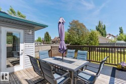 Spacious wooden deck with dark wood railings and a clear glass paneled door - 