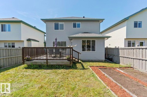 Expansive backyard featuring a multi-level wood deck, manicured lawn, and raised garden beds - 1007 Macewan Close Sw, Edmonton, AB - Outdoor With Exterior