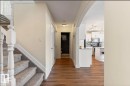 Wood-finish flooring throughout the main hallway, featuring a white painted staircase with gray carpeted treads and white banisters - 1007 Macewan Close Sw, Edmonton, AB  - Indoor Photo Showing Other Room 