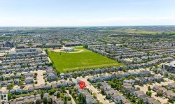 Aerial perspective showcasing a residential neighborhood with detached homes, green spaces, and community buildings - 