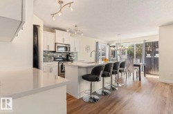 Open-concept kitchen featuring white cabinetry, stainless steel appliances, a tiled backsplash, and light-toned countertops - 