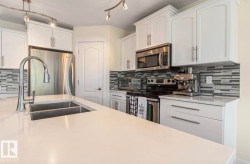 Kitchen featuring a large island with an undermount double basin sink and gooseneck faucet - 