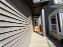 Concrete front steps leading to an orange entry door with glass panels, complemented by gray siding and a dark brown overhead soffit - 2628 Donaghey Crescent Sw, Edmonton, AB 