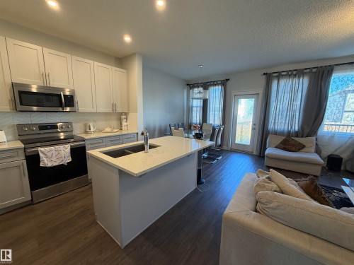 Kitchen with shaker-style cabinetry, stainless steel appliances, and a central island with a double basin sink - 2628 Donaghey Crescent Sw, Edmonton, AB 