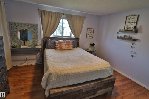 Wood-finish flooring with light-colored walls and a window featuring drapes - 4113 - 42 B Ave, Leduc, AB 