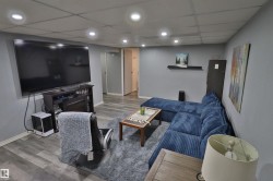 Recessed ceiling lighting, wood-finish flooring, media console with built-in electric fireplace, and neutral wall tones - 