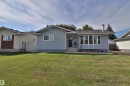 Light blue siding exterior with a dark gray front door, a prominent bay window, a concrete walkway, and a spacious green lawn - 4113 - 42 B Ave, Leduc, AB 