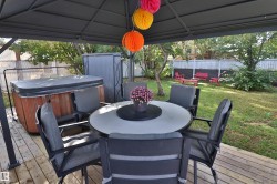 Expansive backyard featuring a wood-finish deck, covered gazebo, and a hot tub - 