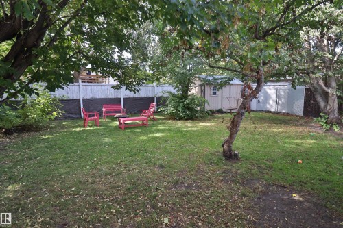 Expansive green lawn with mature trees, fenced perimeter, and a detached storage shed - 4113 - 42 B Ave, Leduc, AB 
