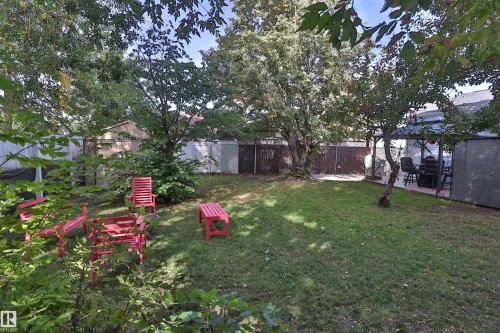 Expansive lawn area with mature trees, privacy fencing, and a hardscaped patio - 4113 - 42 B Ave, Leduc, AB 