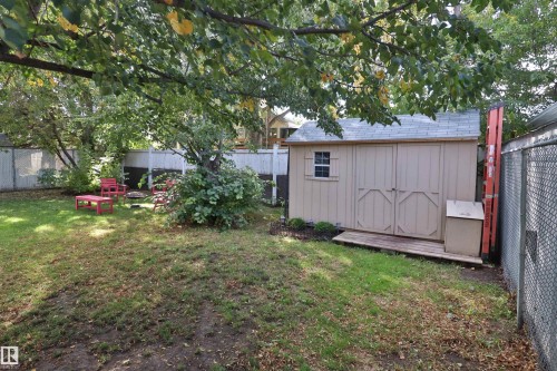 Fenced backyard featuring mature trees, a storage shed with a shingle roof, and a wood-slat base - 4113 - 42 B Ave, Leduc, AB 