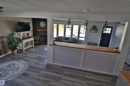 Welcoming entry foyer featuring a wood-finish reception counter with integrated workspace, abundant natural light from multi-pane glass doors and transom windows, and plank-style wood-finish flooring throughout the open common areas - 4113 - 42 B Ave, Leduc, AB 