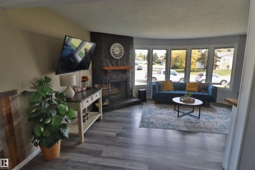 Stone fireplace with wood mantel, bay window, and wood-finish flooring - 4113 - 42 B Ave, Leduc, AB 
