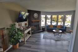 Stone fireplace with wood mantel, bay window, and wood-finish flooring - 