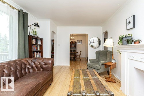 Hardwood-style flooring, white crown molding, white fireplace mantel, and arched doorways - 10507 67 Avenue Nw, Edmonton, AB 