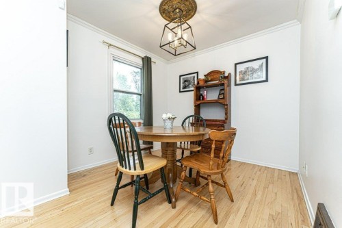 Light wood-finish flooring, white crown molding, and a prominent window - 10507 67 Avenue Nw, Edmonton, AB 