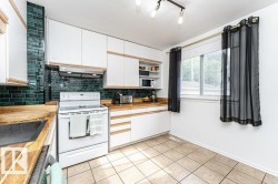 Kitchen featuring white cabinetry, wood-finish countertops, subway tile backsplash, and ceramic tile flooring - 