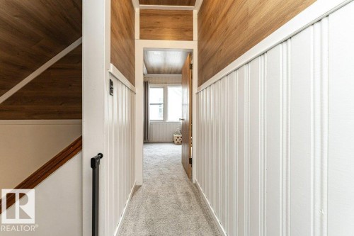 Hallway featuring wood-finish ceiling and wall accents, white beadboard wall panels, and gray carpeting - 10507 67 Avenue Nw, Edmonton, AB 