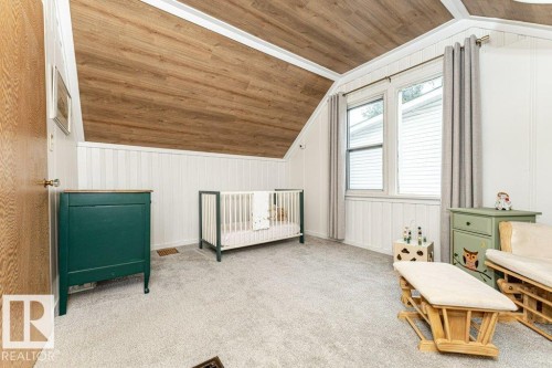 Sloped ceiling with wood-finish planks, white paneled walls, and soft gray carpeting - 10507 67 Avenue Nw, Edmonton, AB 