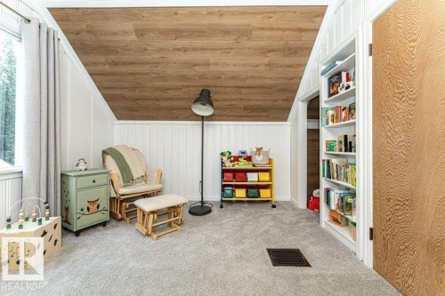 Sloped ceiling with wood-finish paneling, built-in shelving, paneled walls, window with trim, and light gray carpeting - 10507 67 Avenue Nw, Edmonton, AB 