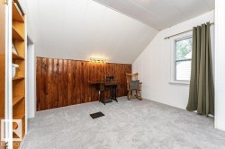 Built-in shelving unit, wood-paneled accent wall, wall-mounted lighting fixture, carpeted flooring, and a double-hung window - 