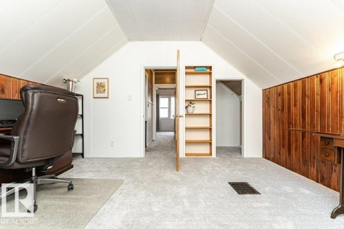 Sloped ceilings with paneling, wood-paneled walls, light-toned carpeting, and a built-in shelving unit - 10507 67 Avenue Nw, Edmonton, AB 