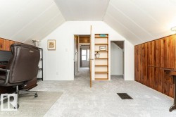 Sloped ceilings with paneling, wood-paneled walls, light-toned carpeting, and a built-in shelving unit - 