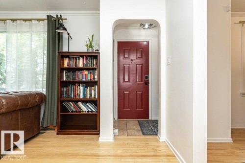 Arched entryway with a paneled door, light wood-finish flooring, and crown molding - 10507 67 Avenue Nw, Edmonton, AB 