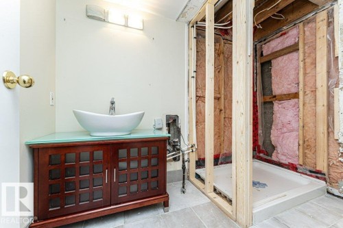 Wood-finish vanity with a vessel sink, a light fixture, and tile flooring - 10507 67 Avenue Nw, Edmonton, AB 