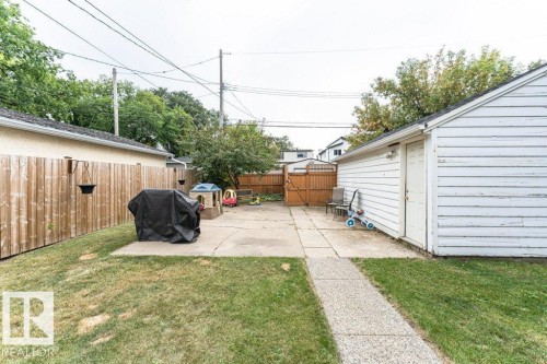 Fenced backyard featuring a concrete patio, concrete pathway, and detached garage - 10507 67 Avenue Nw, Edmonton, AB 
