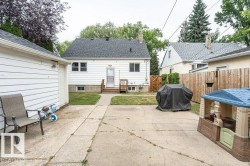 Rear exterior with white siding, a dark shingle roof, and a wood deck - 