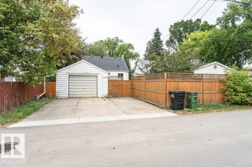 Detached garage with a roll-up door, concrete driveway, and wood privacy fencing - 10507 67 Avenue Nw, Edmonton, AB 