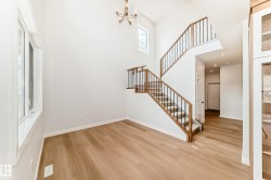Two-story entry with a brass chandelier, wood-finish flooring, and white walls - 