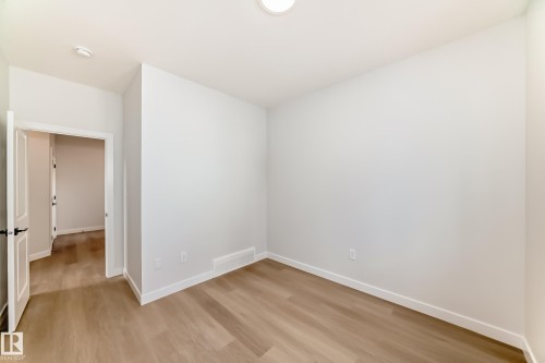 Recessed ceiling light, light wood-finish flooring, white walls, white trim, and a white interior door with black hardware - 47 Meadowgrove Lane, Spruce Grove, AB 